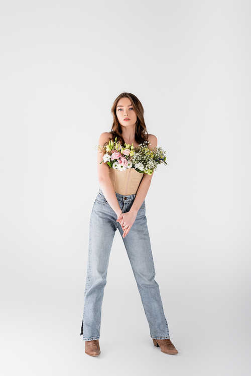 Young model with flowers in blouse  while standing on grey background