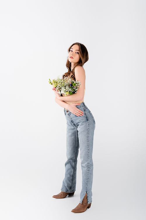 Stylish model with flowers in blouse posing on grey background