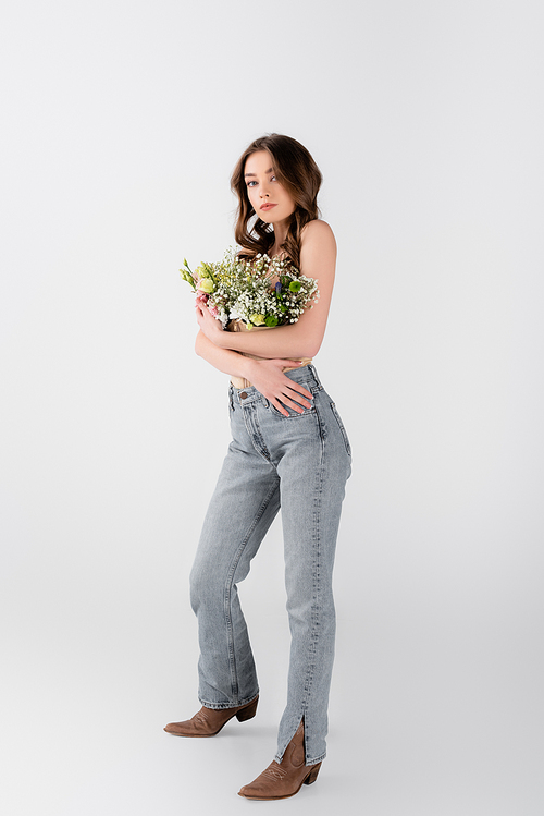 Full length of in jeans and blouse with flowers on grey background