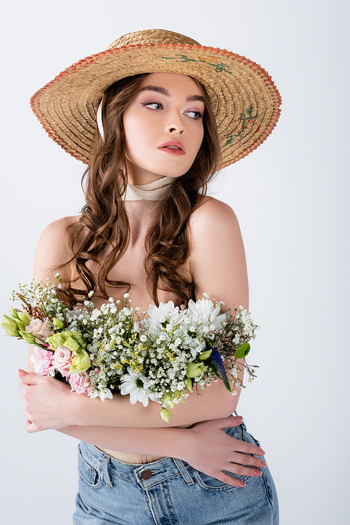 Curly woman in sun hat and flowers in blouse posing isolated on grey