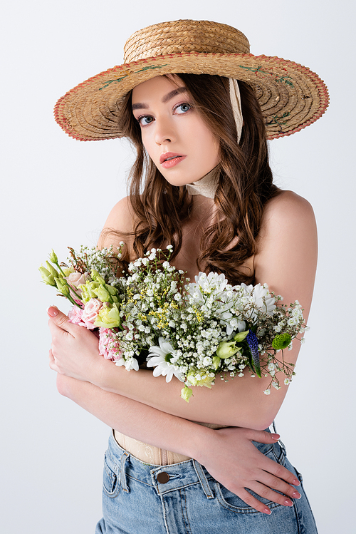 Woman in jeans and straw hat hugging flowers isolated on grey