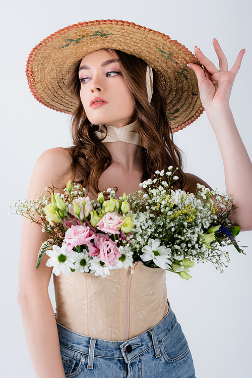 Stylish woman in sun hat and flowers in blouse isolated on grey