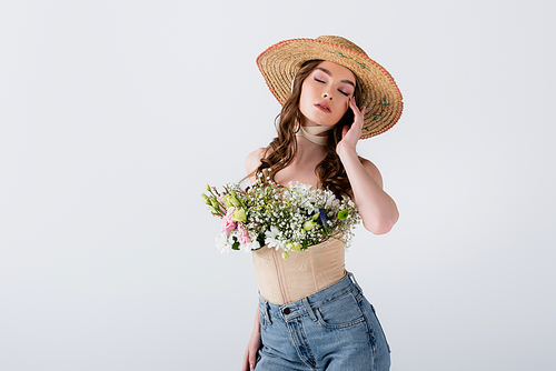 Model in jeans, sun hat and flowers in blouse posing with closed eyes isolated on grey