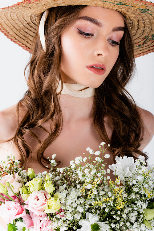 Young woman in stylish sun hat standing near bouquet isolated on grey