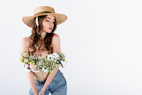 Model with flowers in blouse posing in sun hat isolated on grey