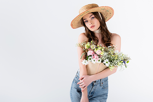 Woman with flowers in blouse posing in straw hat isolated on grey