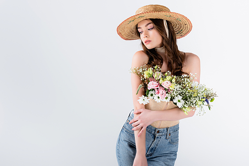 Model in sun hat posing with flowers isolated on grey with copy space