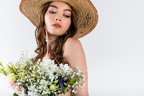 Brunette woman in sun hat looking away near bouquet isolated on grey