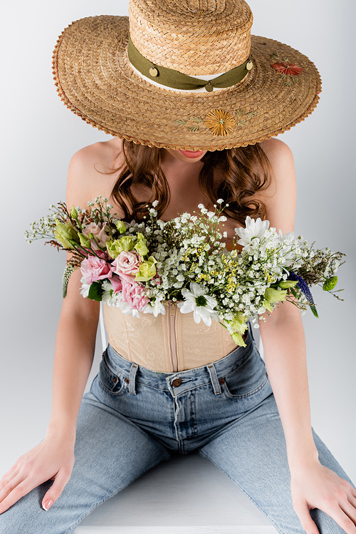 Flowers in blouse of woman in sun hat isolated on grey
