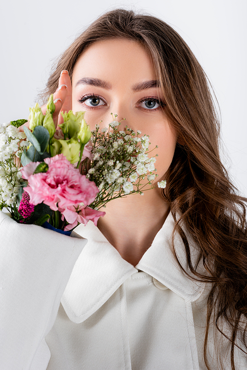 Brunette woman  near flowers in sleeve of coat isolated on grey