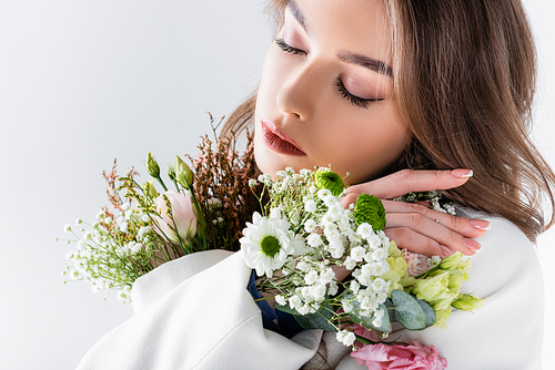 Woman posing with different flowers in jacket isolated on grey