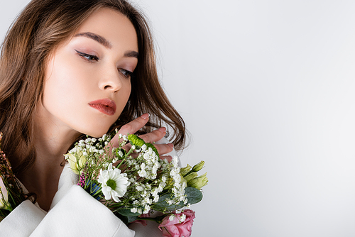 Brunette woman with flowers in sleeve looking away isolated on grey