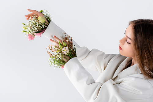 Woman looking at flowers in sleeves of blazer isolated on grey