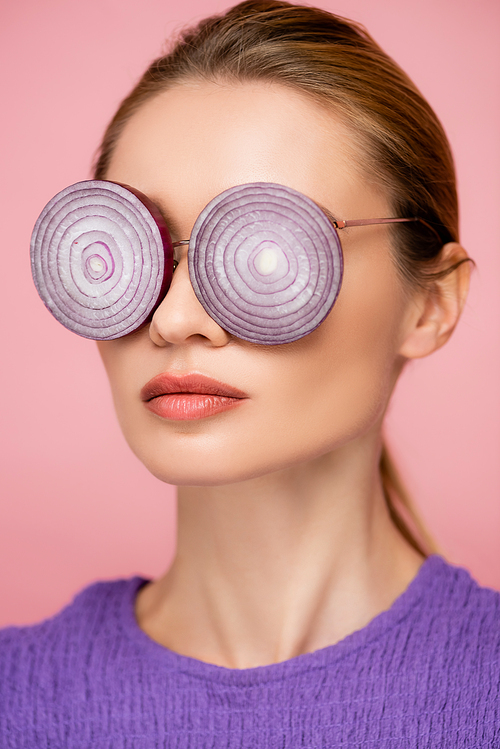 close up view of woman with onion rings eyeglasses isolated on pink, surrealism concept