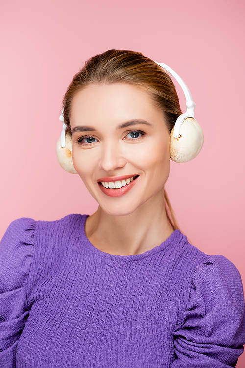 cheerful woman with mushrooms in headphones  isolated on pink