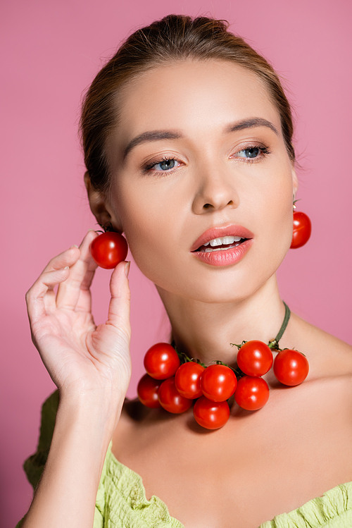 sensual woman in necklace and earrings made of fresh red cherry tomatoes on pink