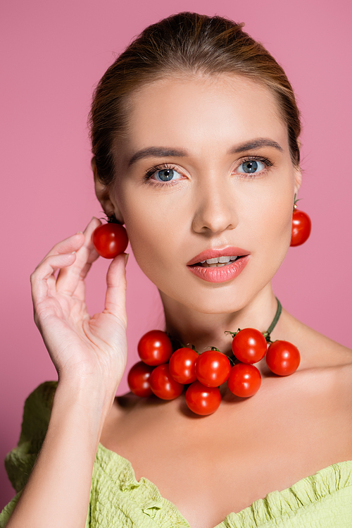 sensual woman in necklace and earrings made of red cherry tomatoes on pink