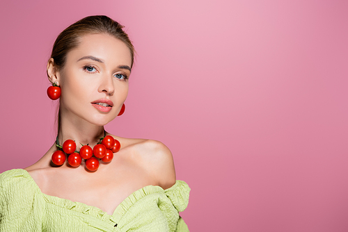 pretty woman in green blouse and necklace made of cherry tomatoes isolated on pink