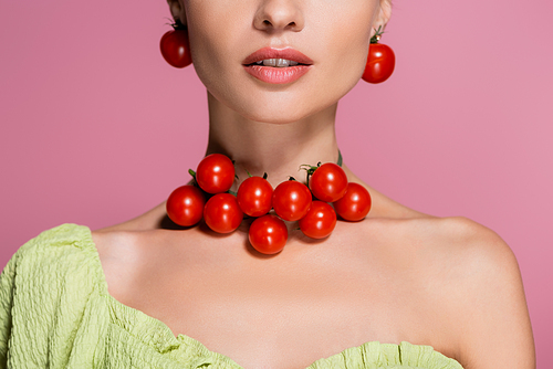 partial view of young woman in red cherry tomatoes earrings and necklace isolated on pink
