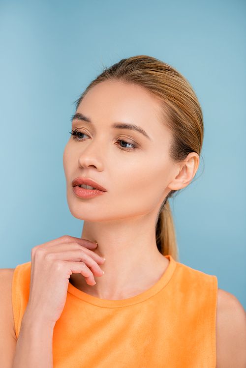 charming woman with natural makeup looking away isolated on blue