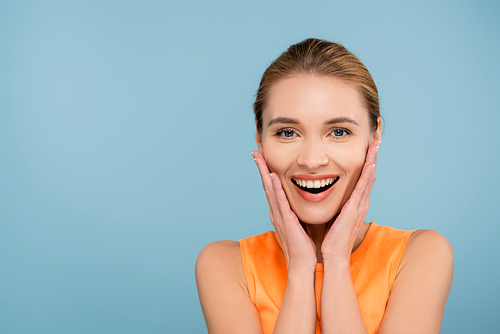 pretty young woman with natural makeup touching face isolated on blue