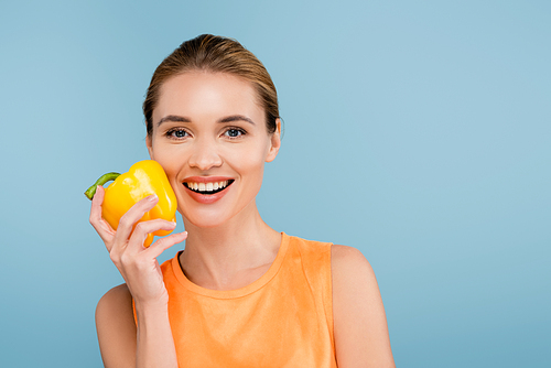 charming woman with natural makeup holding bell pepper isolated on blue