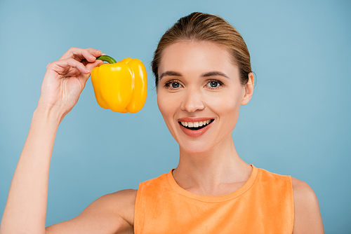 pretty woman with natural makeup holding yellow bell pepper isolated on blue