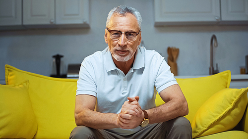 smiling grey haired man  while sitting on sofa at home