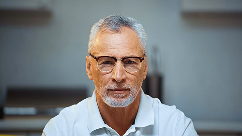 positive elderly man in eyeglasses  at home