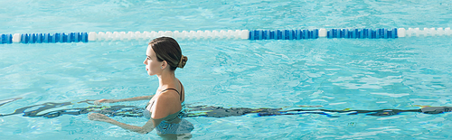 Side view of young woman swimming in pool in spa center, banner