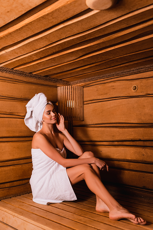 Pleased woman with closed eyes relaxing in wooden sauna
