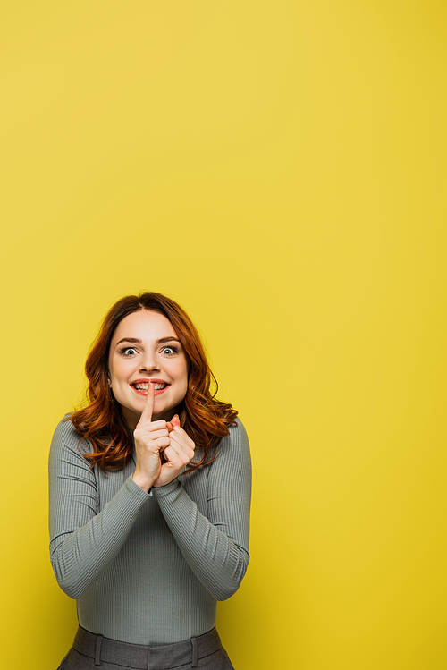 happy woman with curly hair showing hush sign isolated on yellow