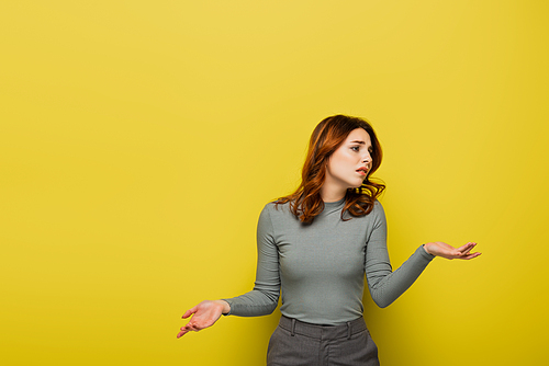 confused woman with curly hair showing shrug gesture on yellow