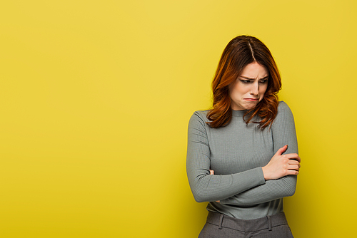 offended woman with curly hair standing with crossed arms on yellow