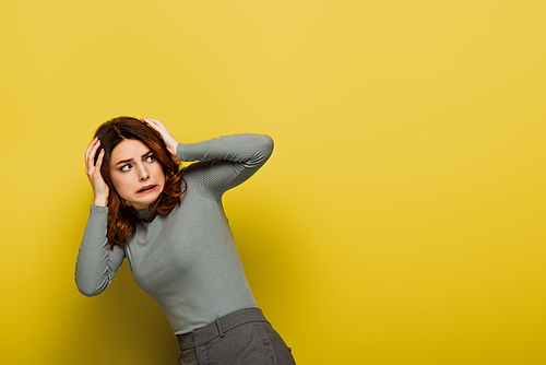 scared woman with curly hair looking away on yellow