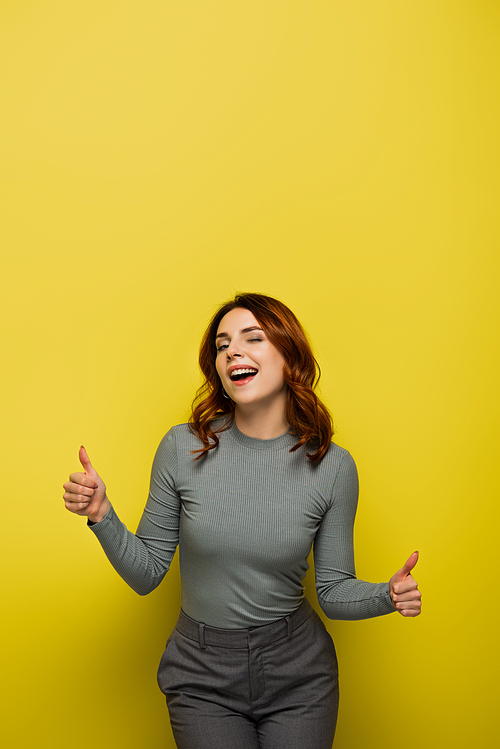positive woman with curly hair showing thumbs up on yellow