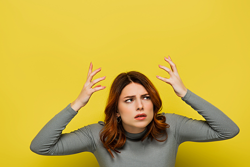 stressed woman with curly hair gesturing isolated on yellow