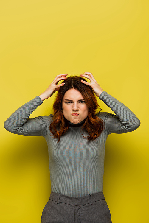 stressed woman with curly hair touching head and  on yellow