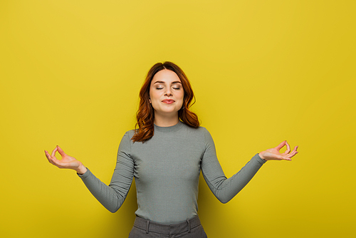 woman with curly hair smiling while meditating on yellow