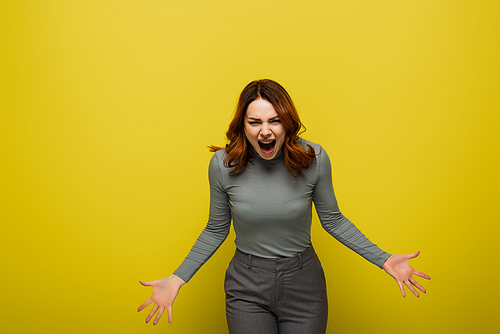 angry woman with wavy hair screaming isolated on yellow