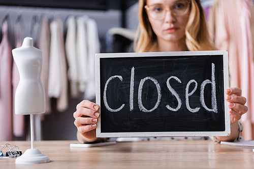 businesswoman holding board with closed lettering in showroom, blurred background