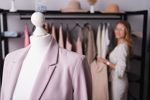 selective focus of blazer on mannequin near showroom proprietor on blurred background