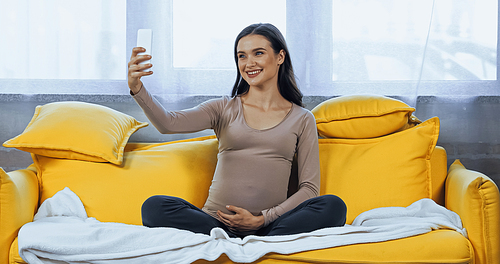 Young pregnant woman smiling during selfie at home