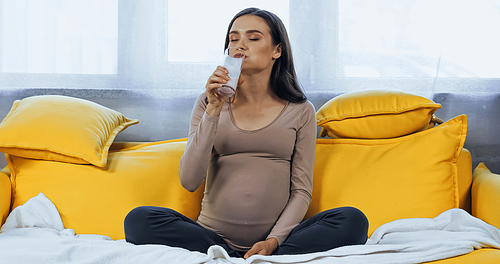 Pregnant woman drinking milk in living room