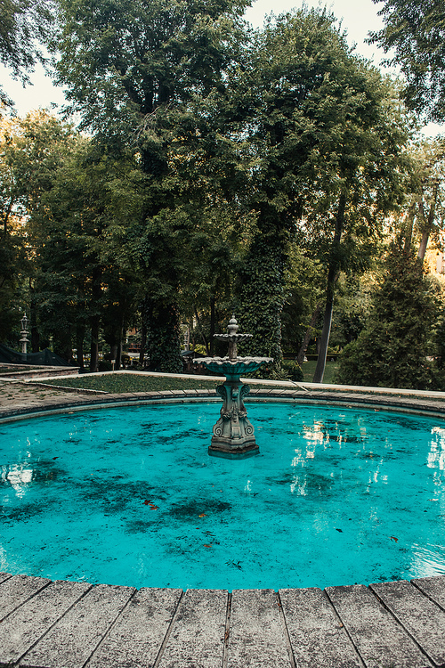 decorated fountain with blue water in green park