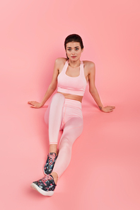 Young sportswoman in sportswear  on pink background
