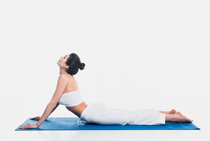 Side view of young woman practicing yoga on fitness mat on white background