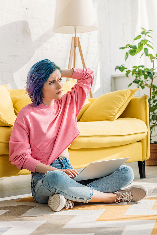 Thoughtful freelancer with colorful hair working with laptop on floor