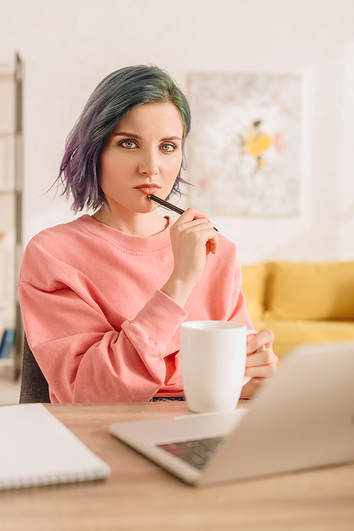 Selective focus of freelancer with colorful hair  and holding pen at table