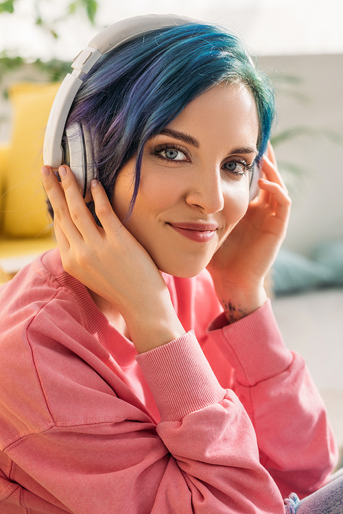 Beautiful woman with colorful hair and headphones listening music,  and smiling